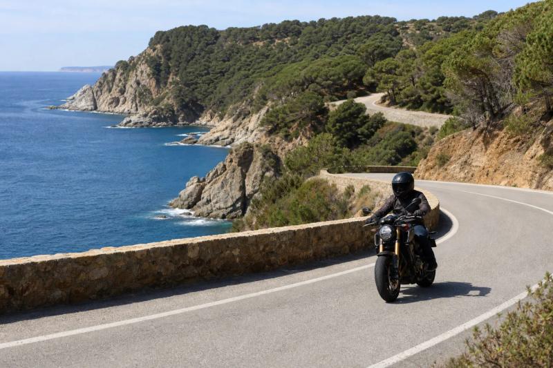 A winding coastal road with the sea and rocky coves below, seen from a headland on the Costa Brava