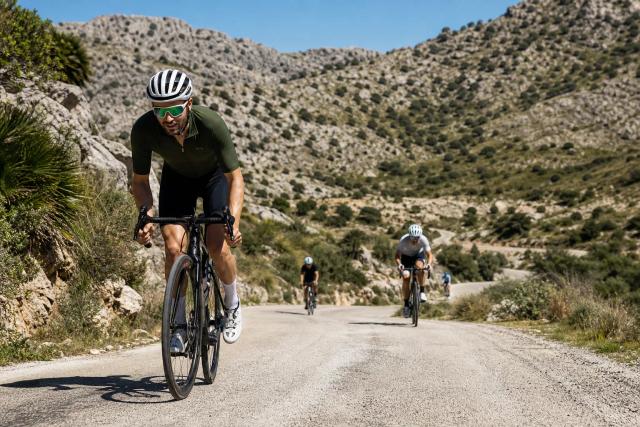 Group of road cyclists climbing a switchback mountain pass in the Pyrenees with a support van parked at the roadside