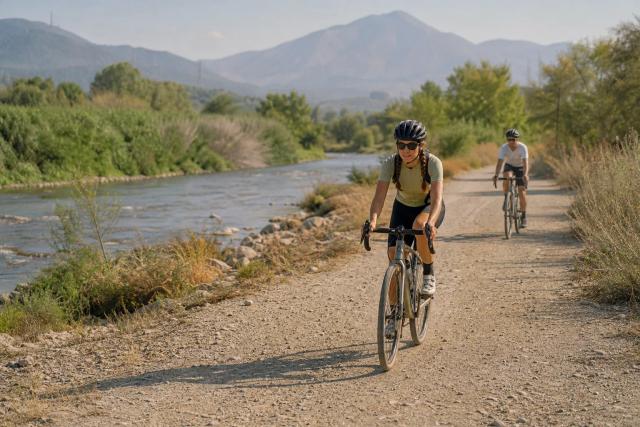 Cyclists riding gravel bikes along a wide riverside track near Marbella