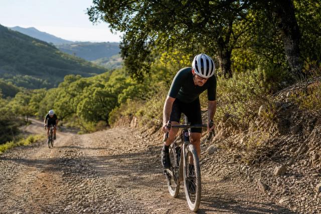 Gravel riders climbing a loose track across open volcanic ground near Marbella